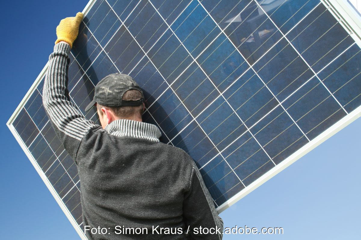 Ein Handwerker trägt ein Solarmodul.